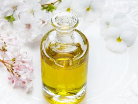 A bottle of homemade scented body oil, surrounded by flowers.