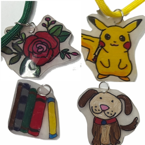 a selection of four shrink art pendants, a red rose with green leaves on a green cord, a yellow Pikachu on a yellow cord, a multicolored set of books and a brown and white dog