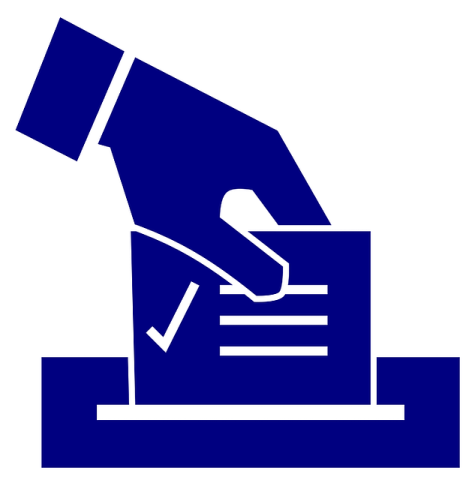 A hand places a ballot into a ballot box