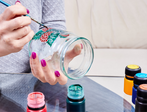 Person painting a glass with a brush and paints