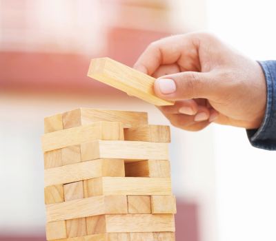 A hand of someone putting a piece on a Jenga tower