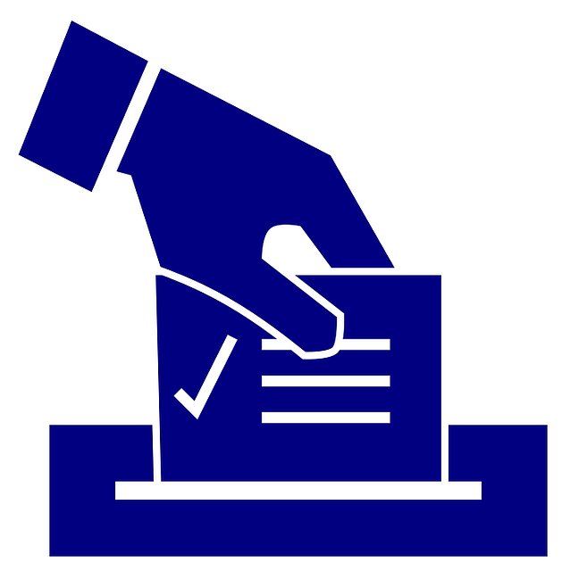 A hand places a ballot into a ballot box